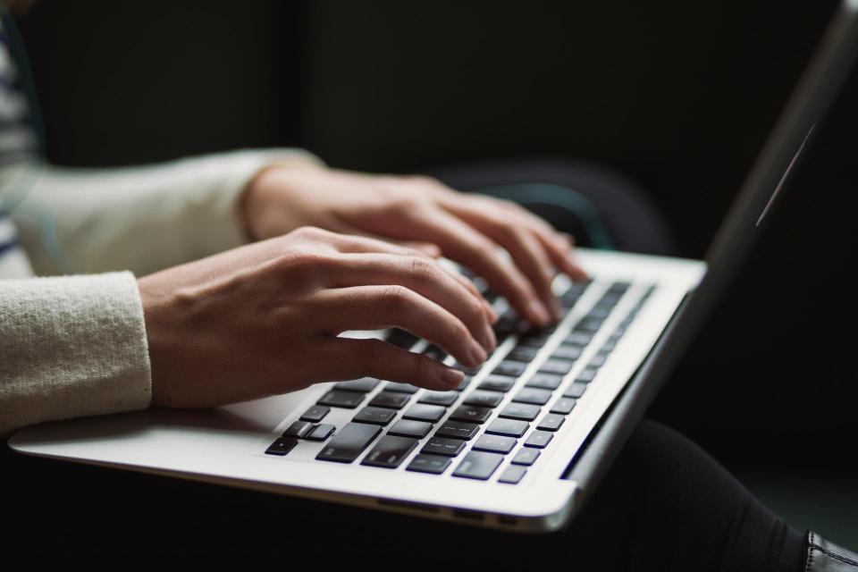 close up of person typing on keyboard of laptop