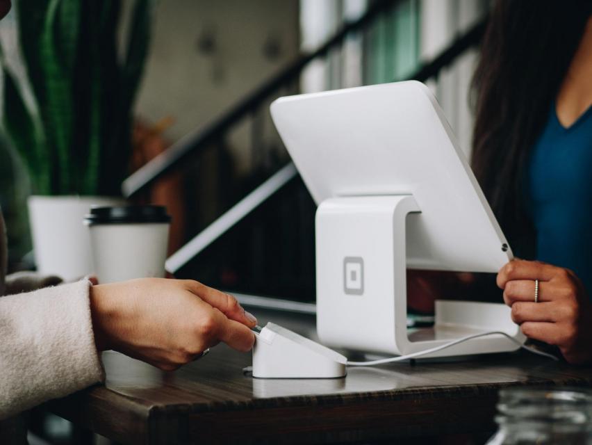 white computer with square retail software and cardreader on counter with person making a purchase
