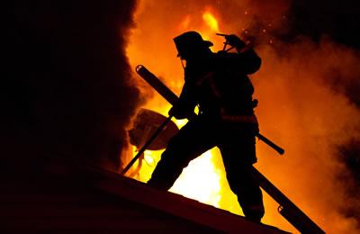 A firefighter silhouetted by fire