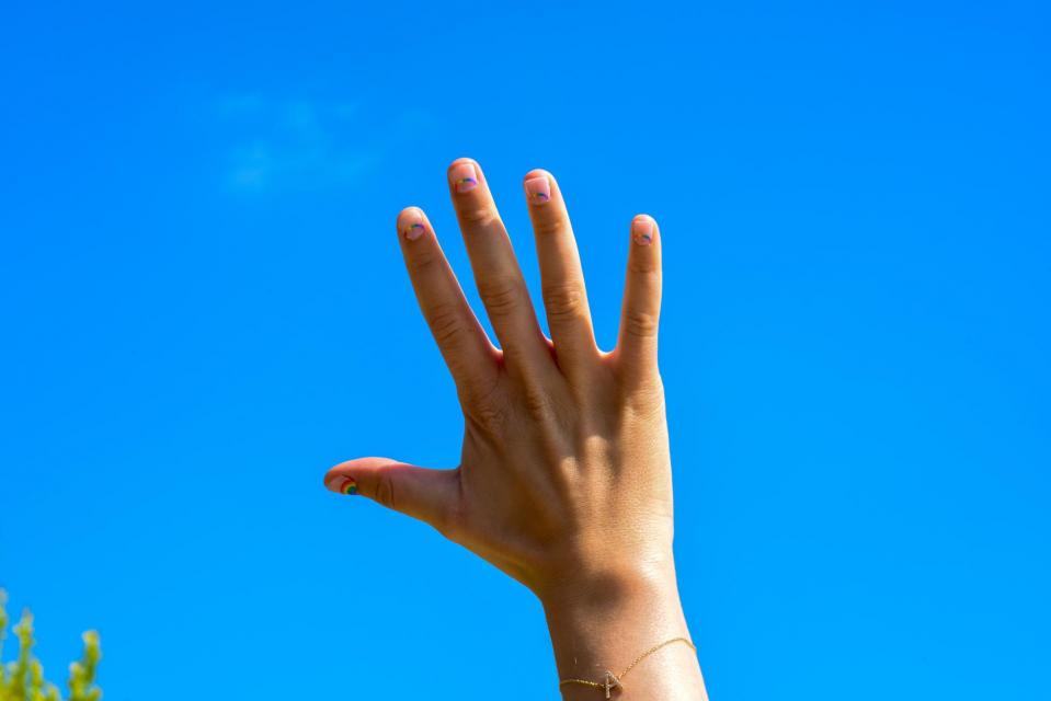a hand raised against a blue sky background