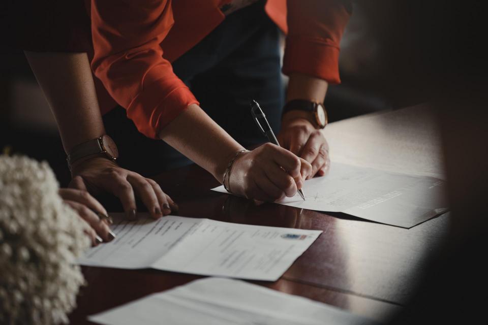 People leaning over table signing paperwork